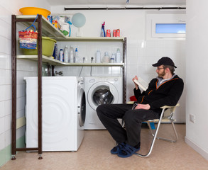 Man Reading a Book in the Laundry Room