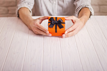 Love concept. Man holding orange gift with black ribbon in hands. Women's day. St. Valetine's day