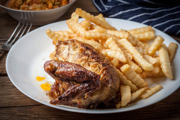 Roasted chicken with french fries on a plate.