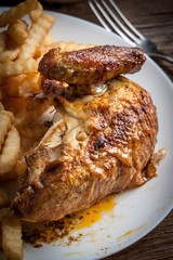 Roasted chicken with french fries on a plate.