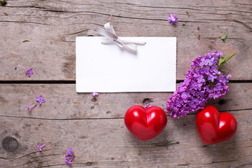 Empty tag,  two red hearts and fresh violet lilac flowers on age