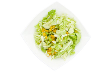 Vegetable salad of cabbage, corn and cucumber in the white plate isolated