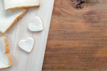 Bread cut in the shape of hearts on wooden table