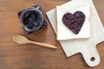 Toast with jam in shape of hearts on wooden background. Top view