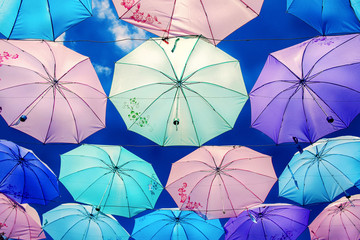 Colorful umbrellas background. Colourful umbrellas urban street decoration. Hanging Multicoloured umbrellas over blue sky. Bright Colors backdrop