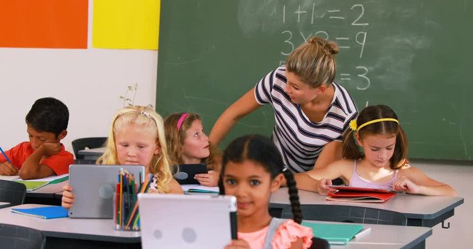 Teacher teaching kids on digital tablet in classroom at school 4k