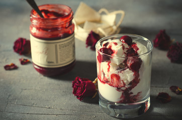 Sundae Ice cream with cherry in chocolate topping, and dried rose flowers on dark background. Love, Valentine's day concept. Copy space