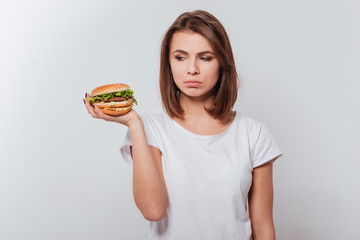 Confused young lady holding fastfood