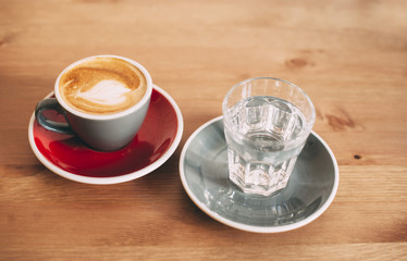 fresh morning cappuccino coffee and a glass of water on a wooden background