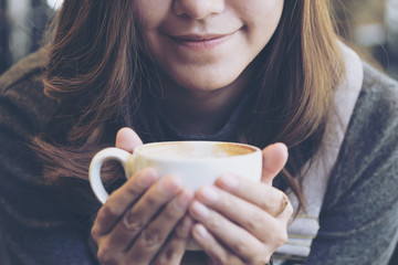 Closeup image of Asian woman drinking hot coffee with feeling good