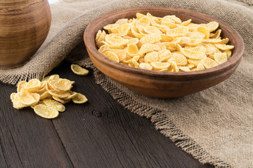 Corn flakes in a ceramic bowl on the old wooden table.