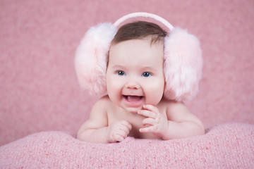 Beautiful little girl in pink warm headphones