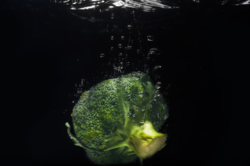 Fresh green broccoli dropped into water isolated