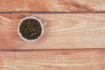 dried chinese tea leaves in a small bowl over wooden background