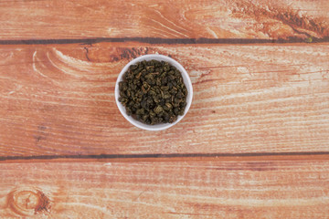 dried chinese tea leaves in a small bowl over wooden background