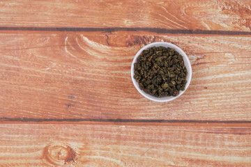 dried chinese tea leaves in a small bowl over wooden background