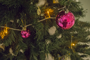 Closeup of red bauble hanging from a decorated Christmas tree. Retro filter effect.