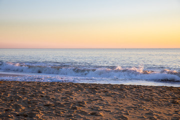 Romantic sunset light on the shore and wave on a winter evening