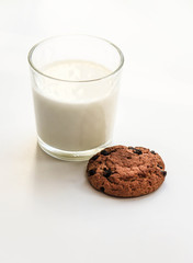 Овсяное печенье на белом фоне и стеклянный стакан молока