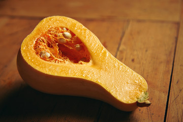 Half splitted juicy fresh bottle squash pumpkin, isolated on rustic wooden table in warm lit