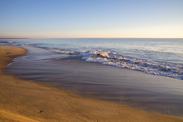 view on a beach at sunset with golden sand and quiet sea