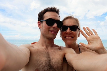 Fototapeta premium Young happy couple is making selfie. Close up portraits of man and woman in vacation on sunny sea beach.