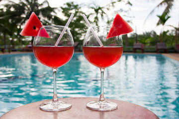Luxury view of couple of wine glasses with cocktails or mocktails with piece of watermelon on edge of glass. Romance in honeymoon vacation in resort.