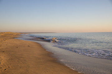 view on a beach at sunset with golden sand and quiet sea
