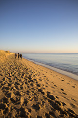 people walking on the beach by romantic winter sunset