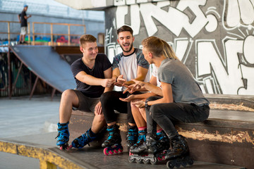 People playing rock paper scissors. Guys on inline skates sitting. Guess or react.