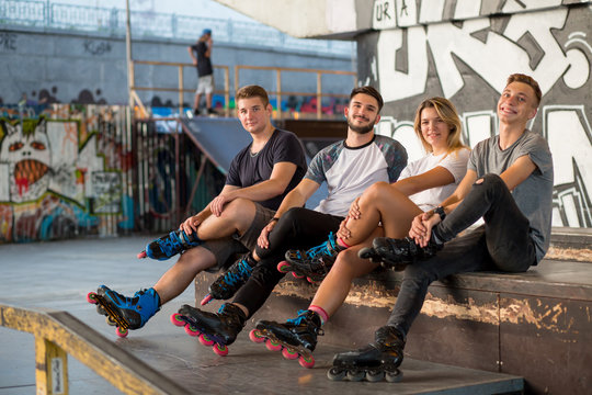 People on rollerblades sitting. Guys and girl in skatepark. Healthy and active youth.