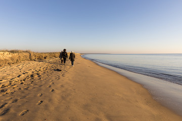 People walking on the beach during golden sunset 