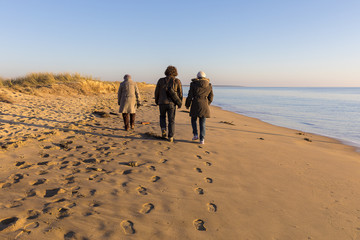 people walking on the beach by romantic winter sunset
