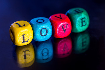 Word "love" of the colored wooden cubes isolated on dark background.