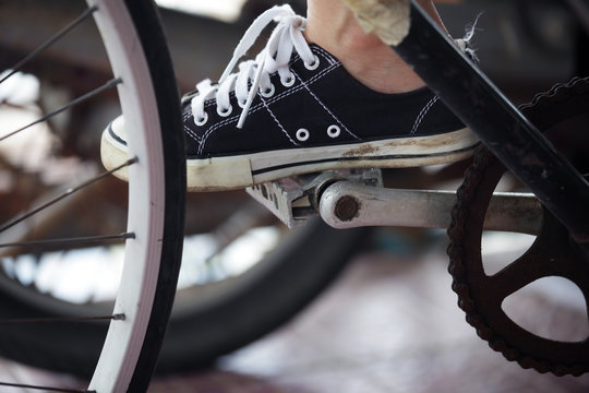 Person riding a vintage bicycle, close up view of sneaker shoe and the pedal