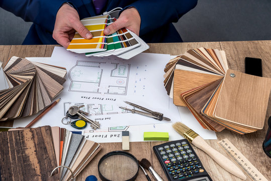 Man architect draws a house plan with color palette for  furniture, work tools.