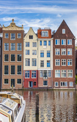 Fototapeta premium Traditional houses and a cruiseboat at the Damrak in Amsterdam