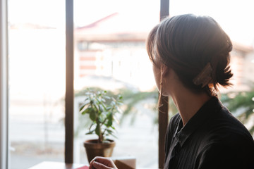 Back view of woman sitting at the table in cafe