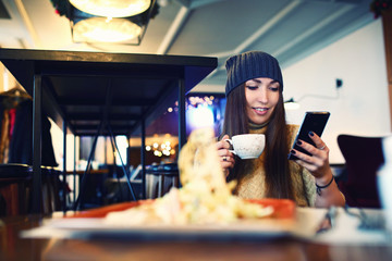 Portret of young female reading sms on the phone in cafe. Tonned. Selective focus.