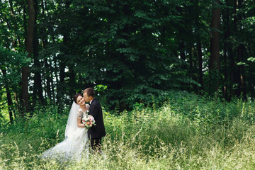 Happy cute newlywed couple hug & kiss in park outdoors
