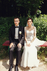 Funny newlywed couple posing on red park bench