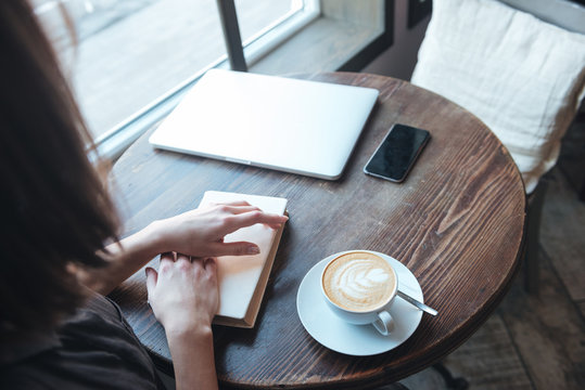 Cropped picture of young woman sitting at table in cafe