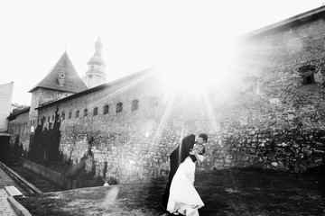Sparkling morning sun illuminates kissing wedding couple