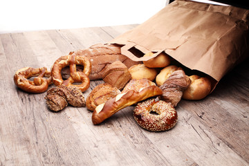 Different kinds of bread and bread rolls on board from above. Kitchen or bakery poster design.