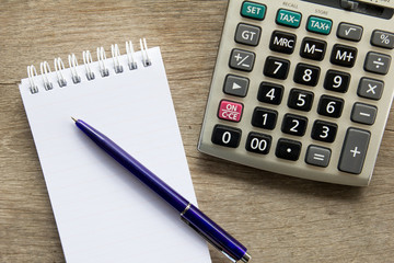 Top view of note book with pen and calculator on wooden table ba