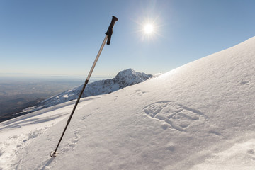 Trekking stick traces of snowshoes in high mountains