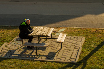Young woman in the distance sitting alone on a bench