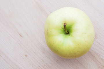 Green or yellow apple in wooden plate.