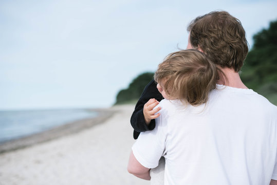 Vater trägt Kind auf dem Arm am Strand
