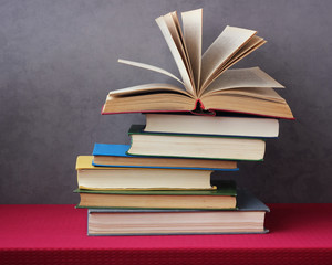 stack of books on the table with a red tablecloth.
